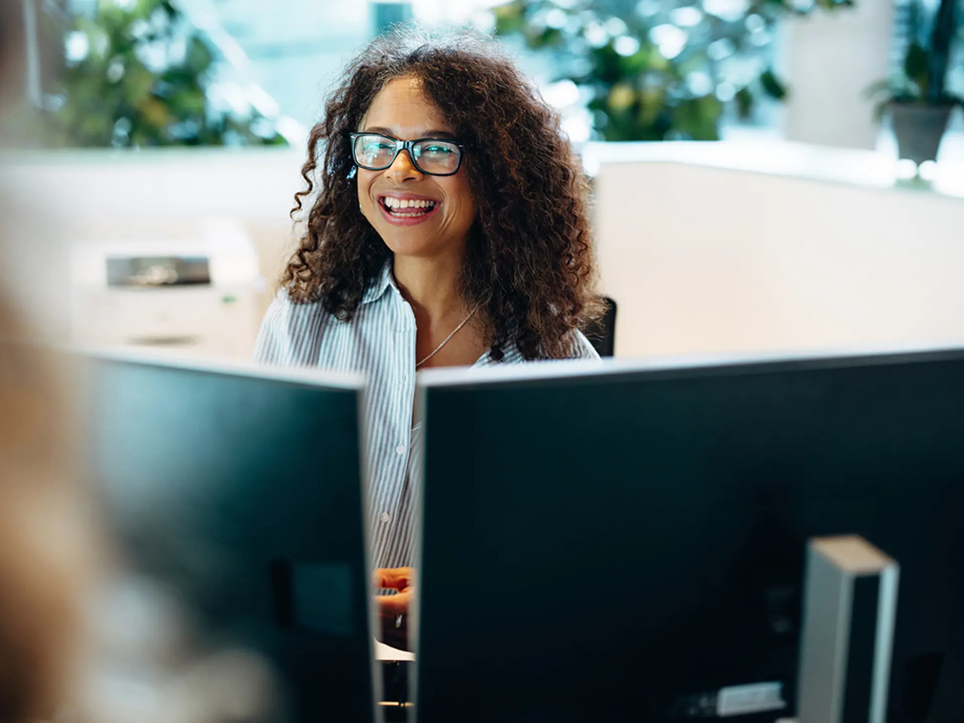 Kvindelig medarbejder bag to computerskærme