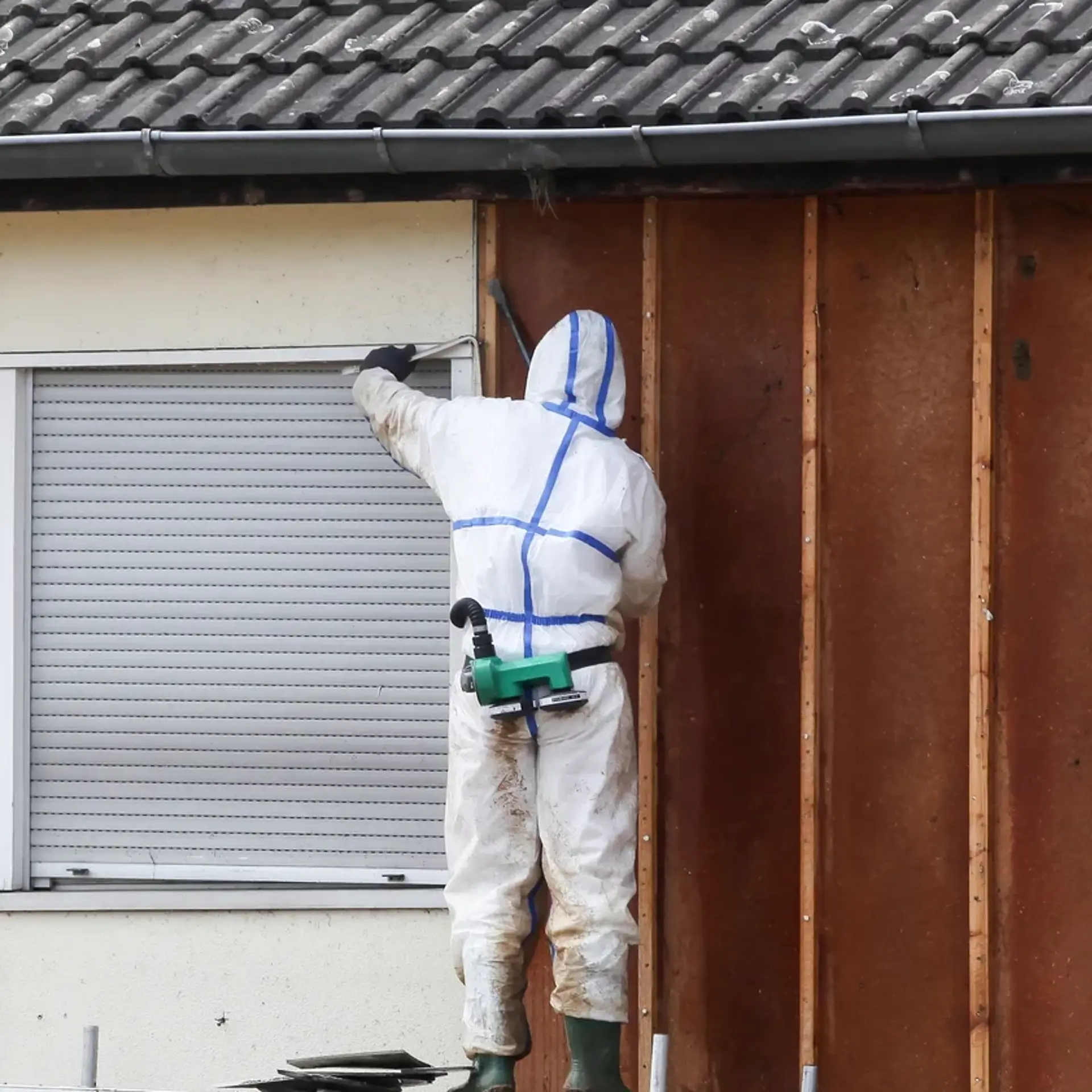 Person i hvid dragt med ryggen til arbejder ved vindue