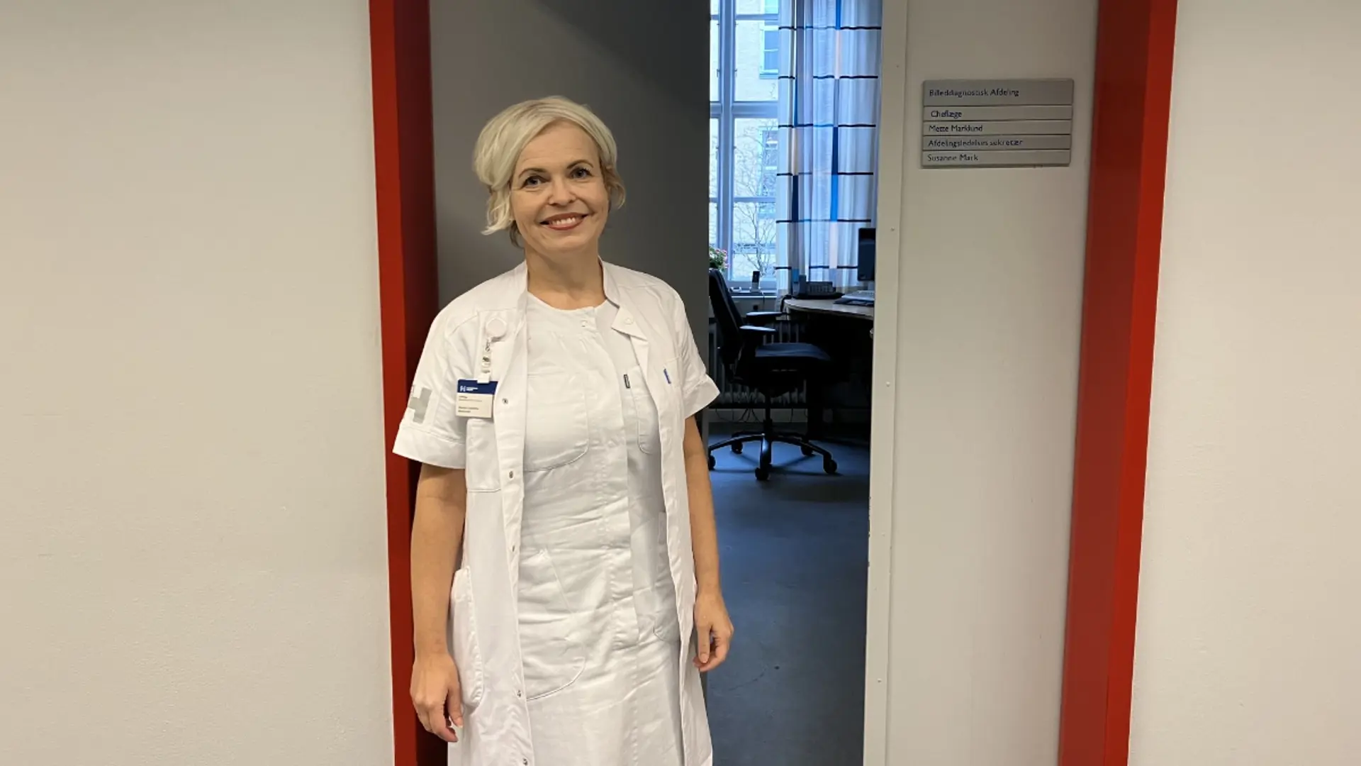 Mette Marklund i hvid kittel foran kontor.