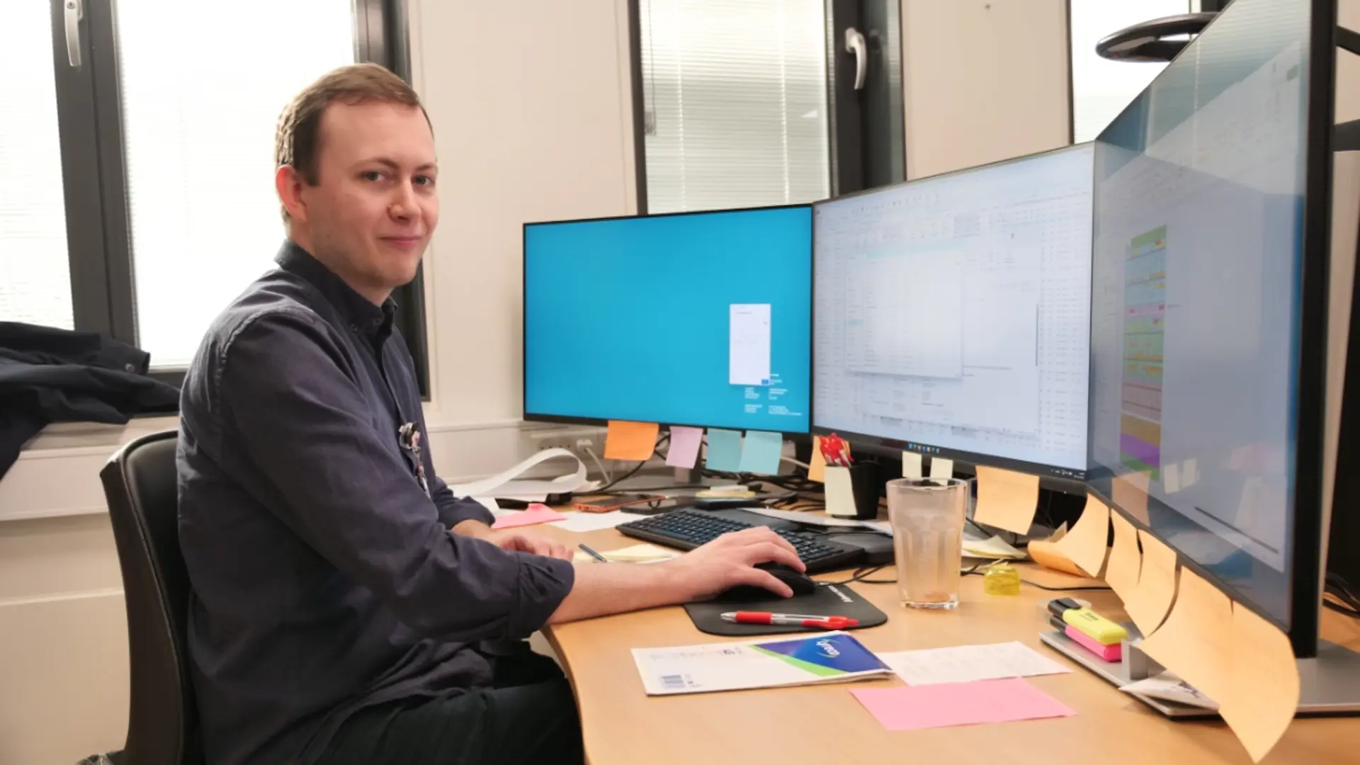 Frederik Balslev Pedersen ved skrivebord foran 3 skærme.
